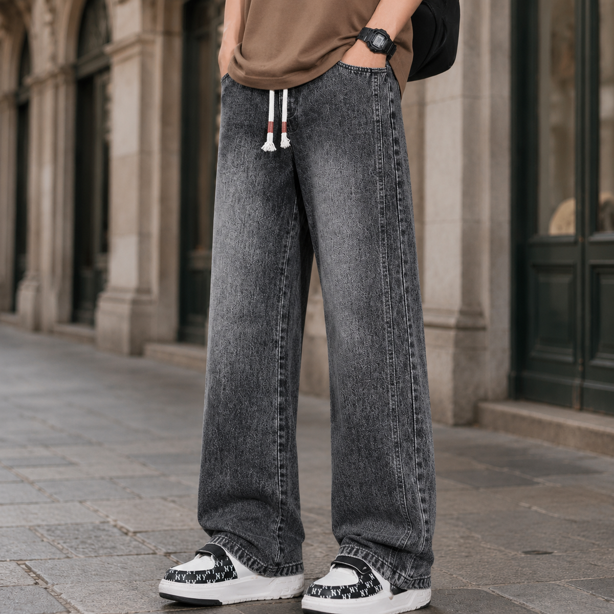 Close-up of the drawstring waist on men's relaxed wide-leg jeans.
