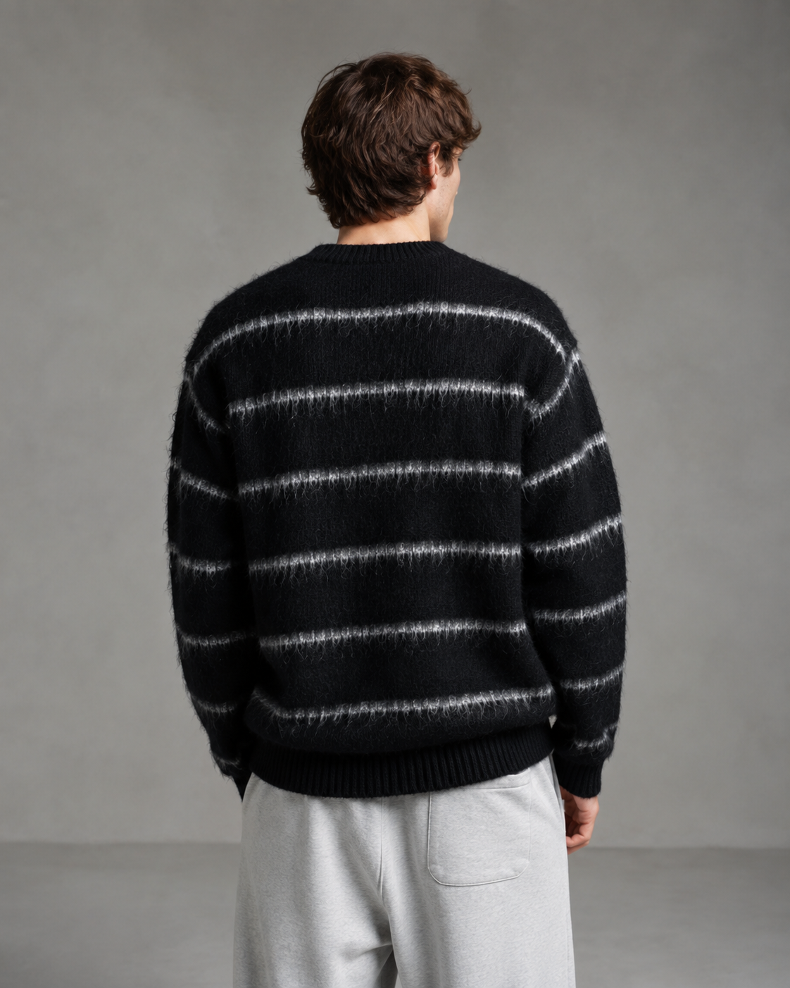 Back view of a men's striped knit sweater showing the relaxed silhouette