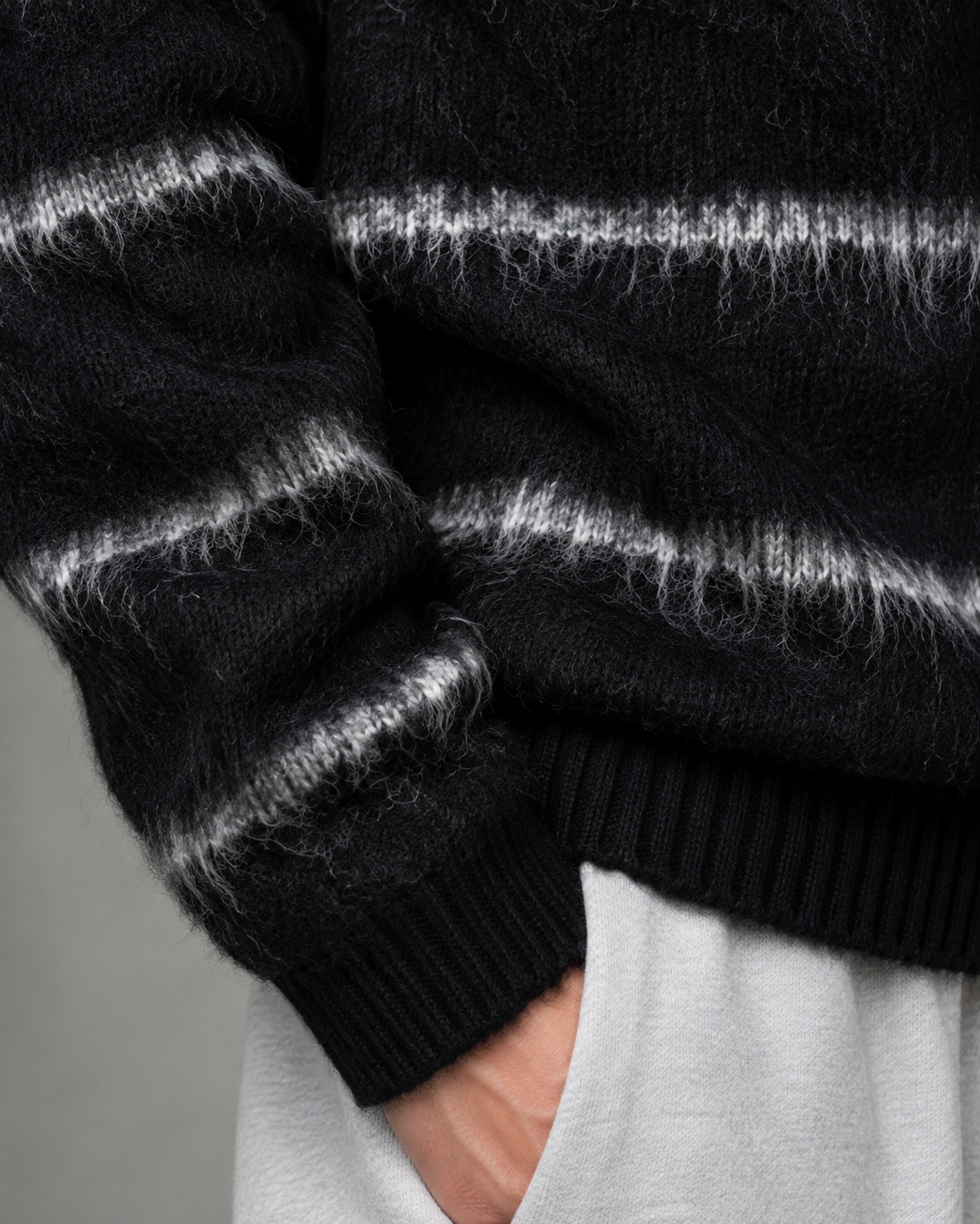 Side view of a men's striped knit sweater with dropped shoulders